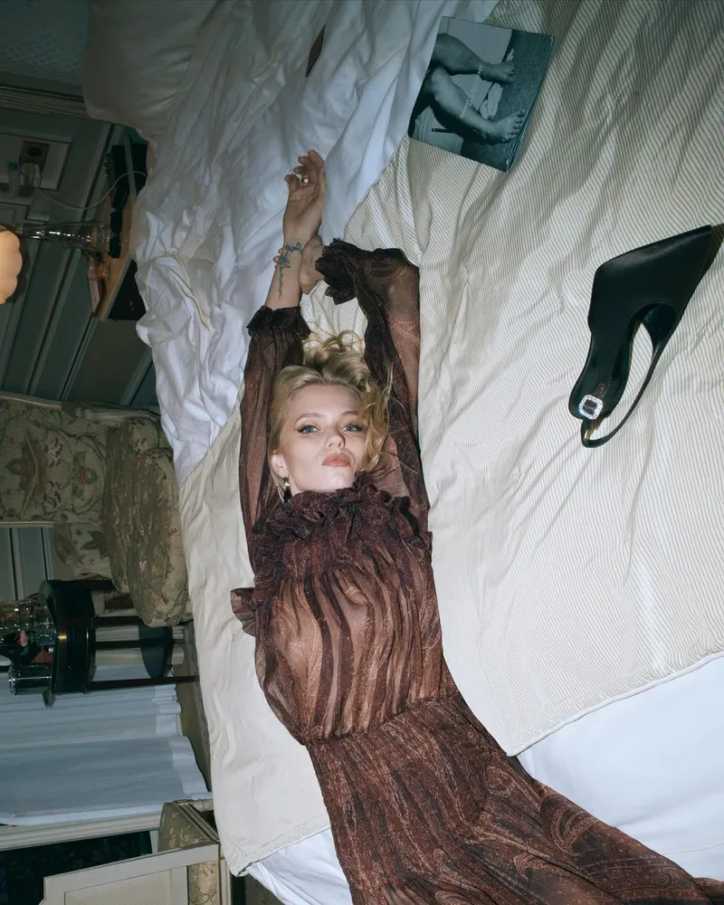 Abbey Lee on the bed in a sheer dress