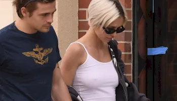 Spy photo of a pretty blonde walking in public braless in a white tank top